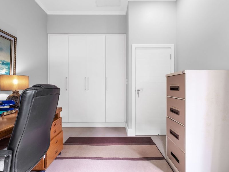 A functional home office featuring clean white built-in cupboards, neutral wall finishes, and a standard internal door.