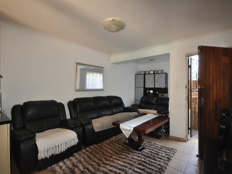 Open plan living area featuring tiled flooring, built-in cabinetry, and direct access to an exterior security gate.