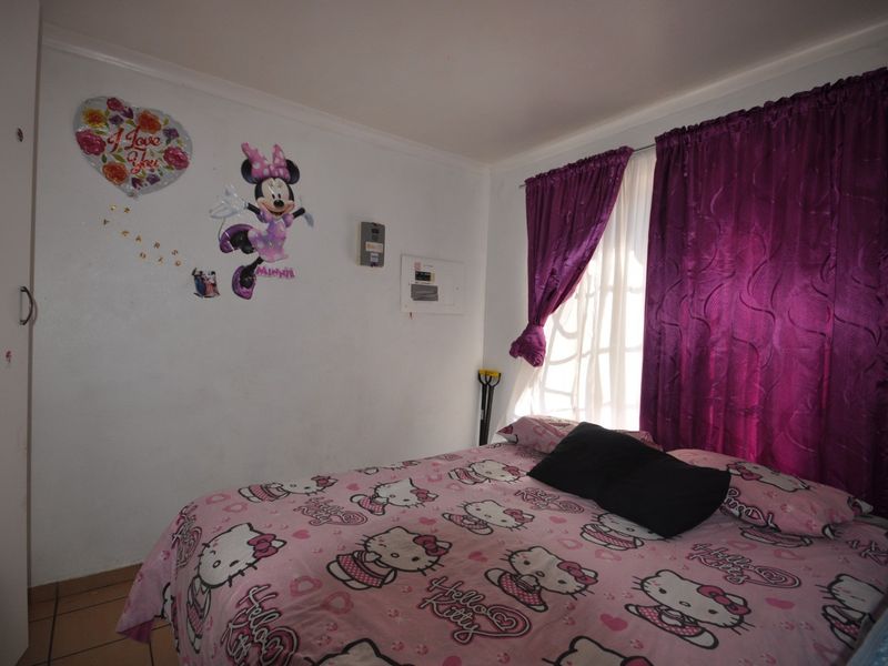 A bedroom featuring a built-in wardrobe and an electrical distribution board mounted on the wall.