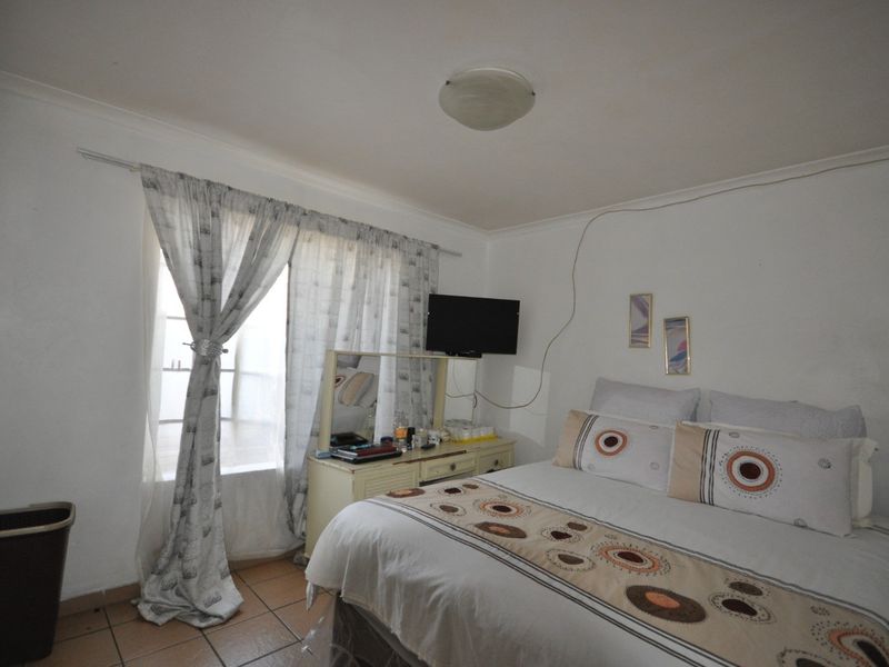 A standard bedroom featuring tiled flooring and a ceiling light fixture, with visible surface wiring on the wall.