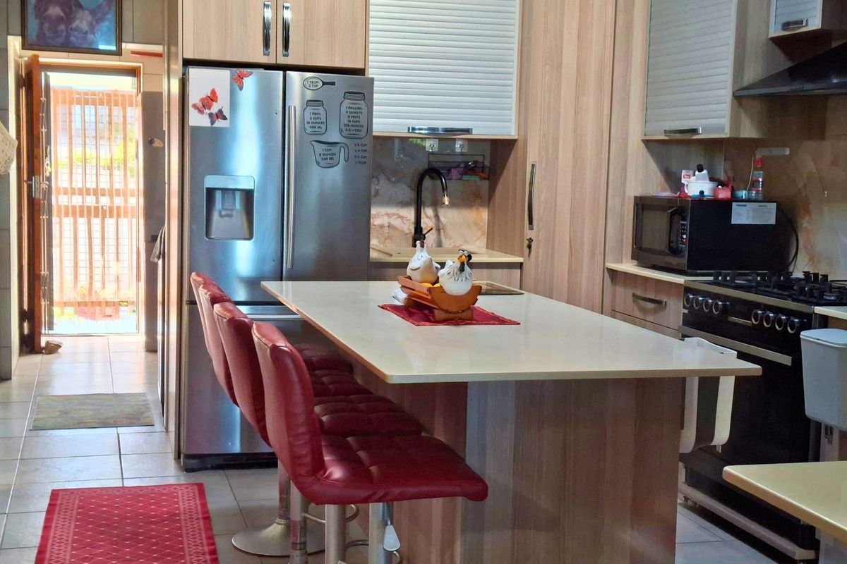 A functional kitchen featuring wood-finish cabinetry, a central island with seating, stone countertops, and integrated gas cooking appliances.