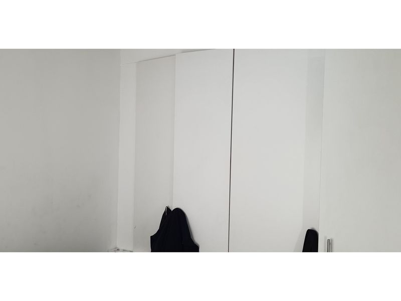 A bedroom interior featuring a white built-in wardrobe with clean lines, offering ample storage space.