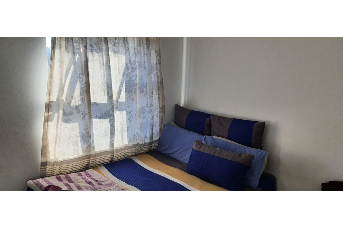 A simple bedroom featuring a window with curtains, providing natural light to the space.