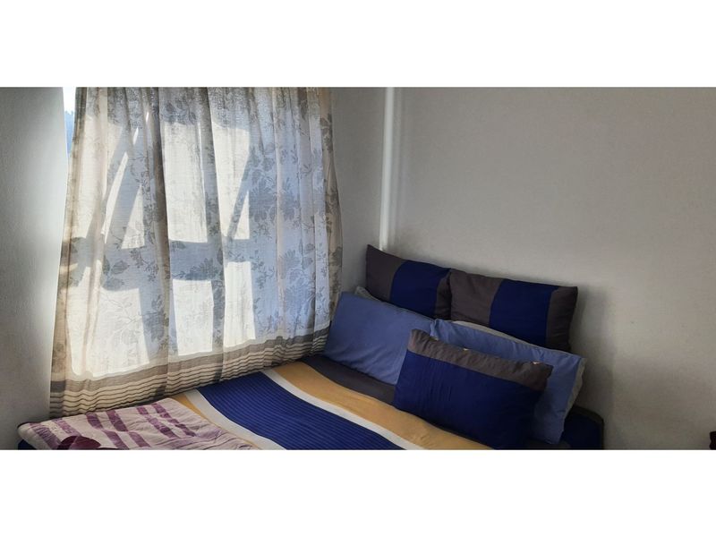 A simple bedroom featuring a window with curtains, providing natural light to the space.
