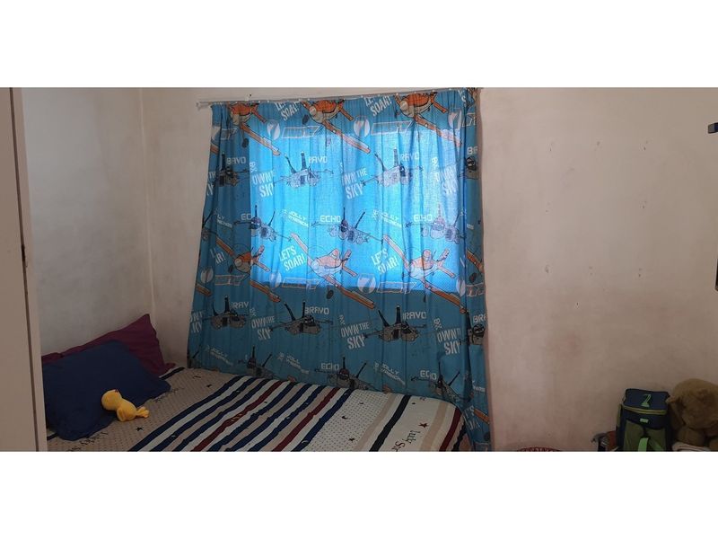 A bedroom featuring a window with a curtain rod, requiring cosmetic updates to the wall finishes.