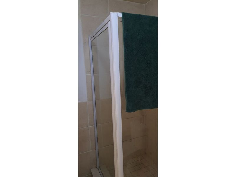 A close-up view of a shower enclosure featuring tiled walls and flooring in a bathroom setting.
