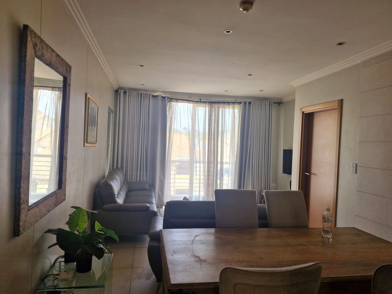 An open-plan living and dining area featuring tiled floors, recessed lighting, and large sliding doors leading to a balcony.