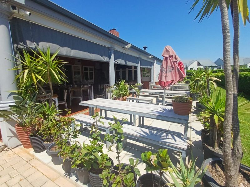 A spacious paved outdoor patio area featuring a retractable awning and structural columns, providing a comfortable space for outdoor dining and relaxation.