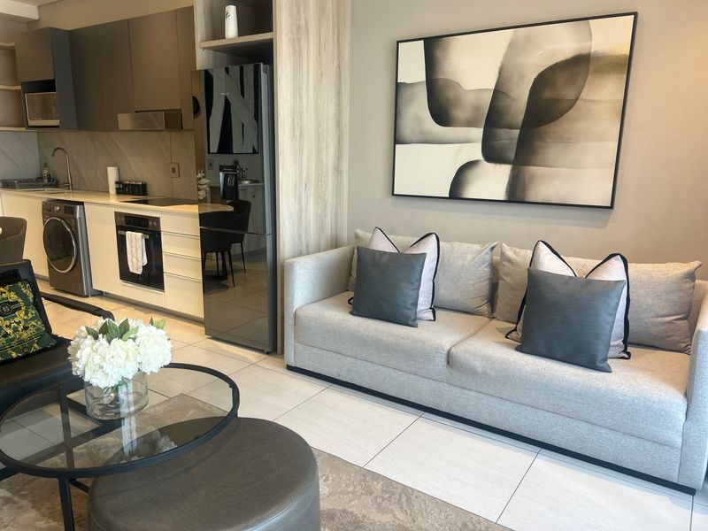 Modern open-plan living area featuring a sleek, well-equipped kitchen with integrated appliances and contemporary tiled flooring throughout.