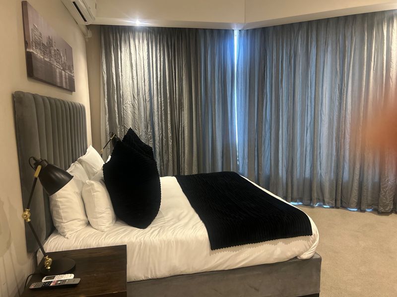 A well-maintained bedroom featuring carpeted flooring, recessed lighting, and a wall-mounted air conditioning unit.