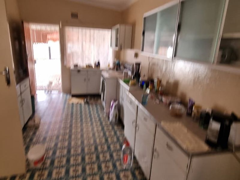 A dated kitchen featuring original cabinetry, tiled flooring, and ample counter space, offering significant potential for a modern renovation.