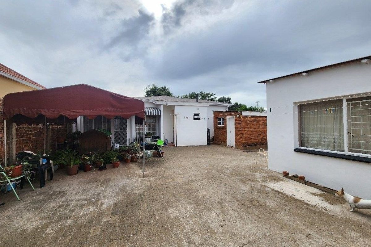 A paved rear courtyard area featuring brick boundary walls and exterior access to the main dwelling and outbuildings.