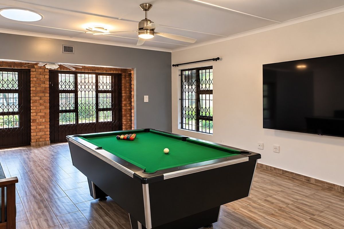 Spacious living area featuring tiled flooring, exposed brick accents, a ceiling fan, and secure access points, currently utilized as a recreational space.