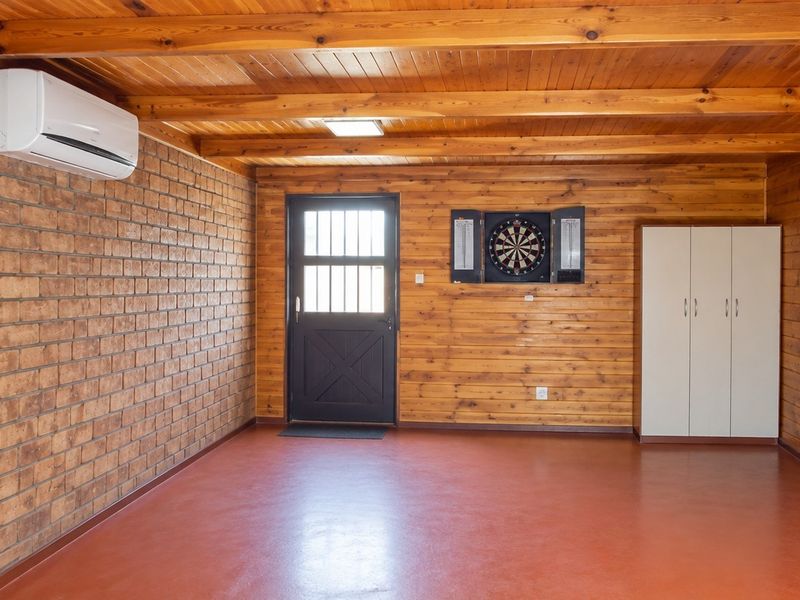 A versatile utility space featuring exposed timber beams, warm wood wall paneling, a face brick feature wall, and a split-system air conditioner.