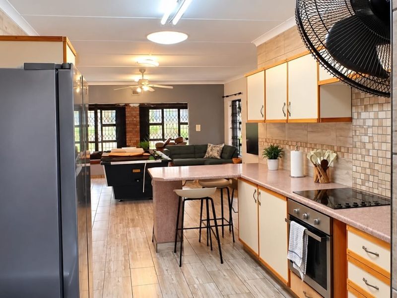Open-plan kitchen and living area featuring tiled flooring, built-in cabinetry with laminate countertops, and integrated cooking appliances.