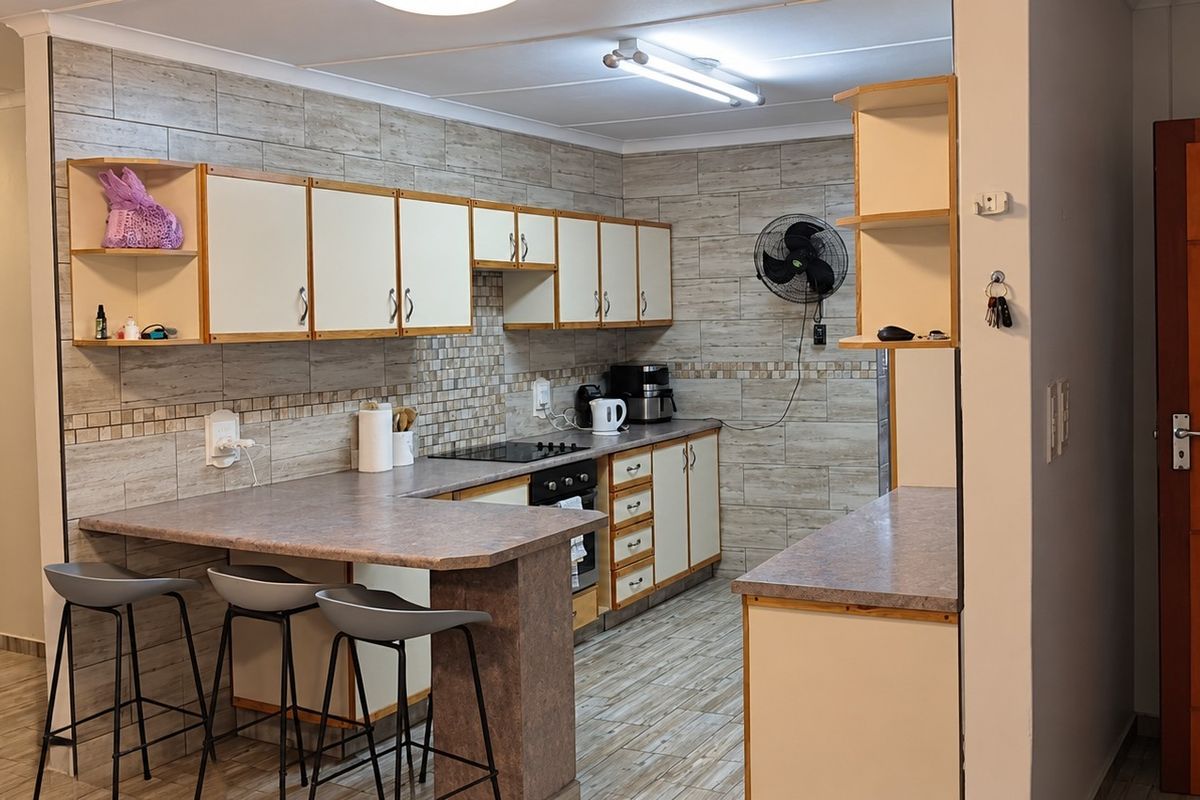 Functional kitchen featuring built-in cabinetry, laminate countertops, tiled backsplash, and integrated oven and hob, with a breakfast bar area.