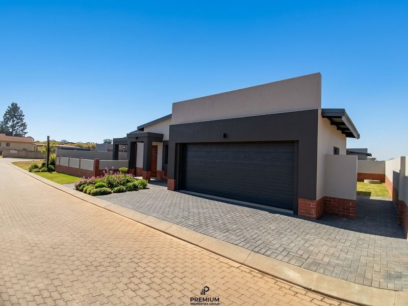 Modern front elevation featuring a double garage, paved driveway, and clean architectural lines with contemporary brick and render finishes.