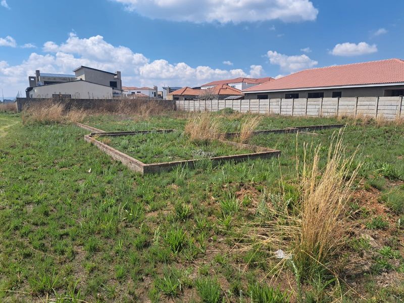 Vacant residential land featuring existing brick foundation footings and a perimeter concrete boundary wall, situated in a developed neighborhood.