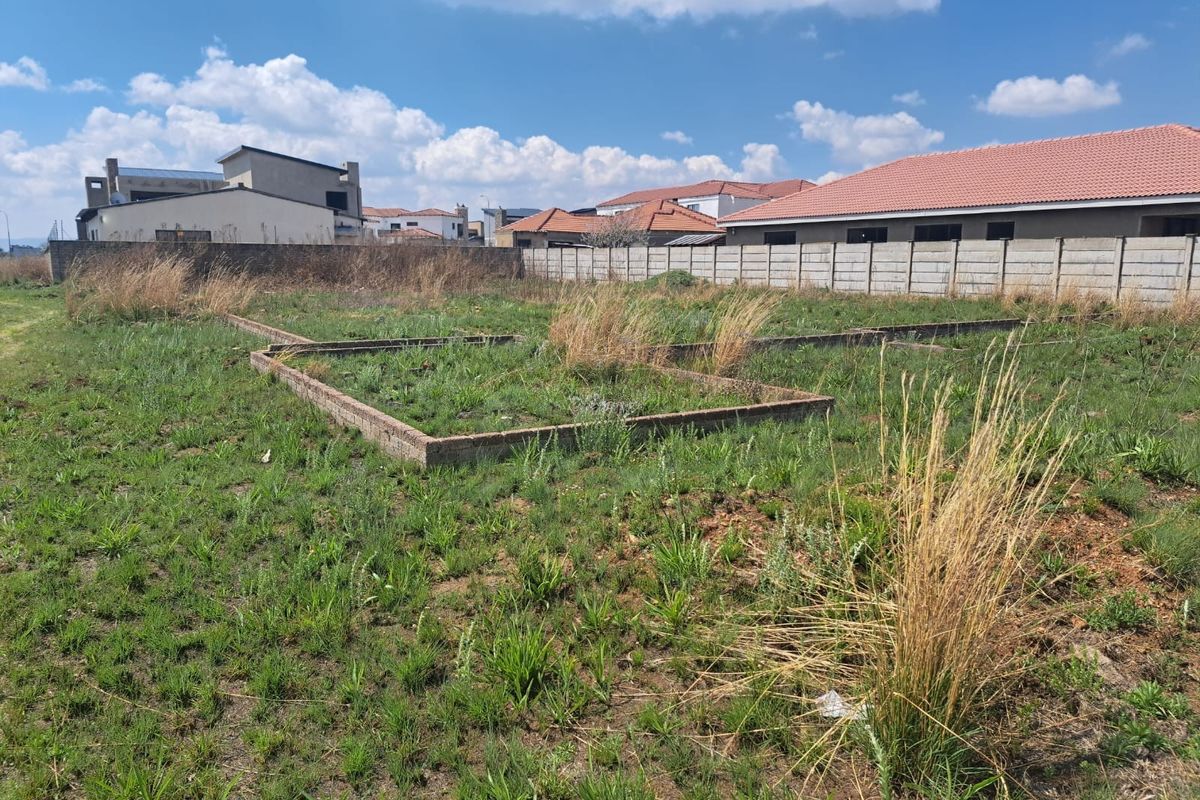 Vacant residential land featuring existing brick foundation footings and a perimeter concrete boundary wall, situated in a developed neighborhood.