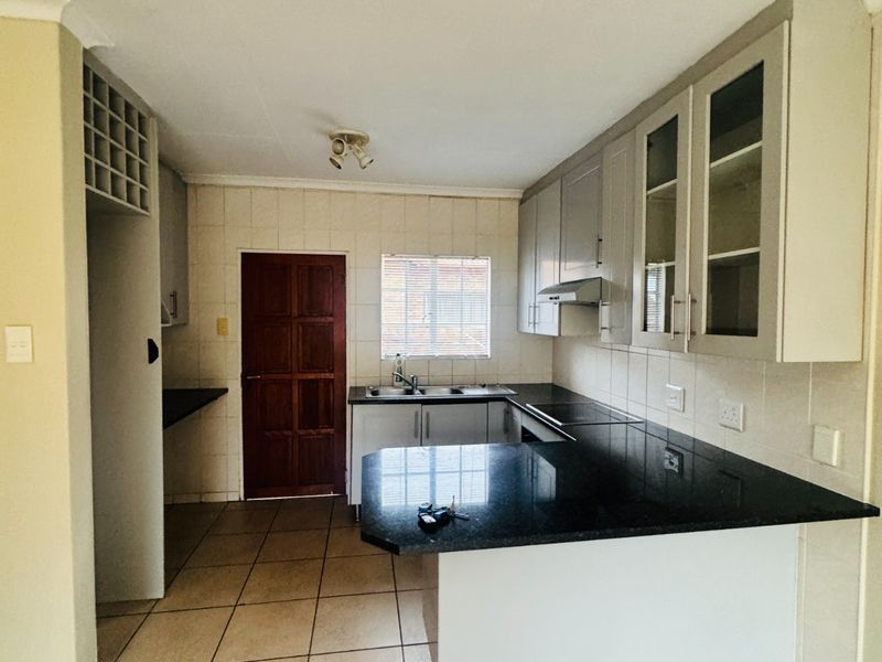 A functional kitchen featuring granite countertops, ample built-in cabinetry, a tiled backsplash, and a dedicated wine rack, offering a clean and practical workspace.