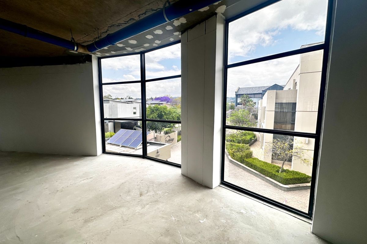 An unfinished open-plan office space featuring large windows with natural light, exposed concrete ceilings, and raw flooring, ready for custom fit-out.