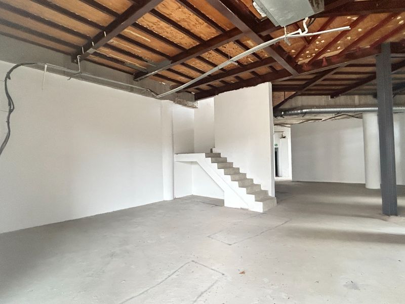 An expansive, open-plan office space featuring industrial-style exposed timber ceilings, steel beams, and concrete flooring, offering a blank canvas for custom fit-outs.