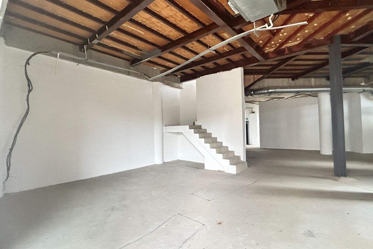 An expansive, open-plan office space featuring industrial-style exposed timber ceilings, steel beams, and concrete flooring, offering a blank canvas for custom fit-outs.