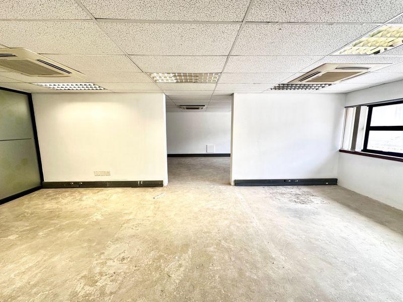 An empty, open-plan office space featuring a suspended ceiling, recessed lighting, ducted air conditioning, and exposed concrete flooring ready for refurbishment.