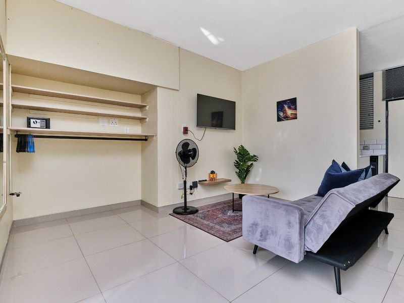 A living area featuring tiled flooring and built-in wall shelving, providing a functional and open space for relaxation.