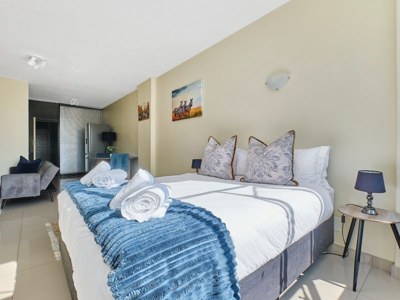 A well-lit bedroom featuring tiled flooring and neutral wall finishes, providing a comfortable and functional living space.