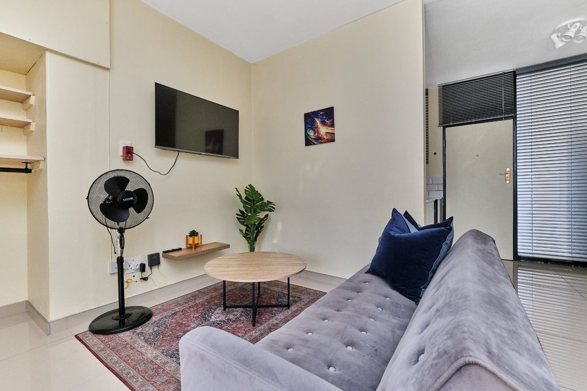 A compact living room featuring tiled flooring, built-in shelving, and neutral wall finishes, providing a functional and versatile space.