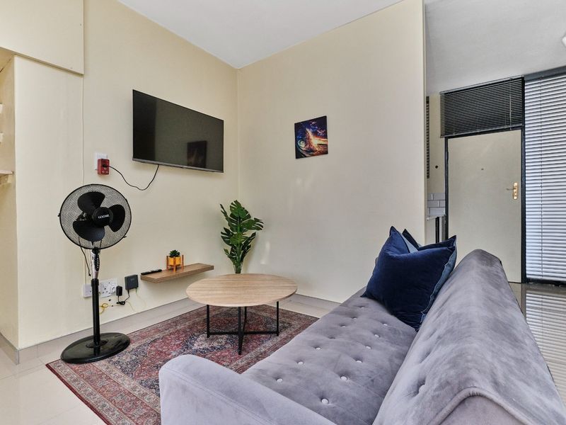 A compact living room featuring tiled flooring, built-in shelving, and neutral wall finishes, providing a functional and versatile space.