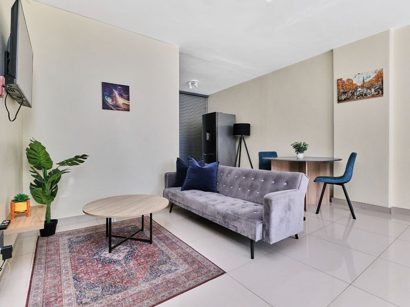 A bright open-plan living and dining area featuring neutral walls and polished tiled flooring, creating a versatile and functional space.