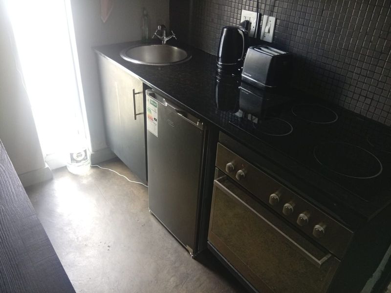 Compact kitchen area featuring a built-in oven, electric cooktop, granite countertops, and a mosaic tile backsplash.