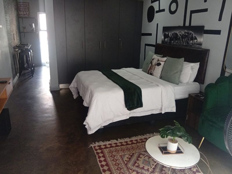 A bedroom featuring polished concrete flooring and dark built-in cupboards, offering a modern industrial aesthetic.
