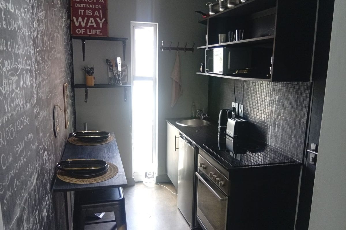 Compact kitchen featuring built-in cabinetry, an integrated oven and hob, mosaic tile backsplash, and a functional sink area.