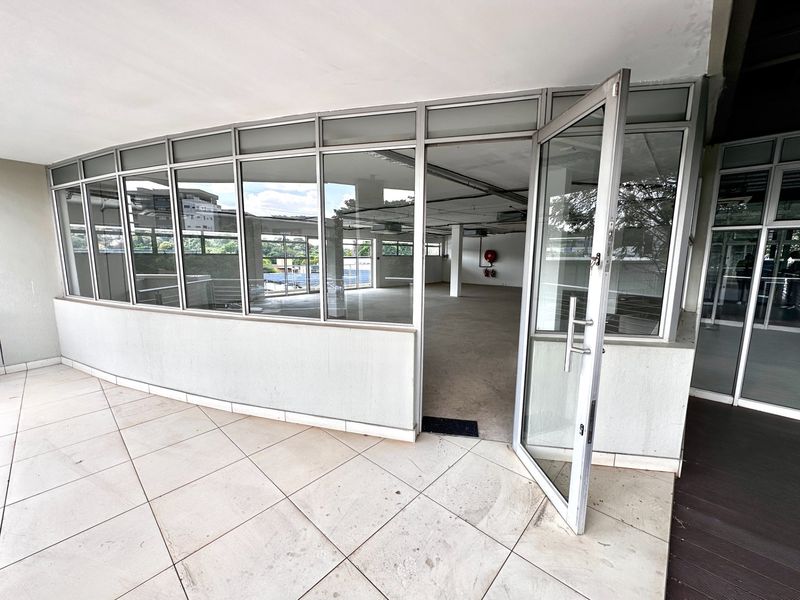 Open-plan office space featuring extensive aluminium-framed glass partitioning, tiled flooring, and exposed ceiling services, providing a bright and versatile commercial work environment.