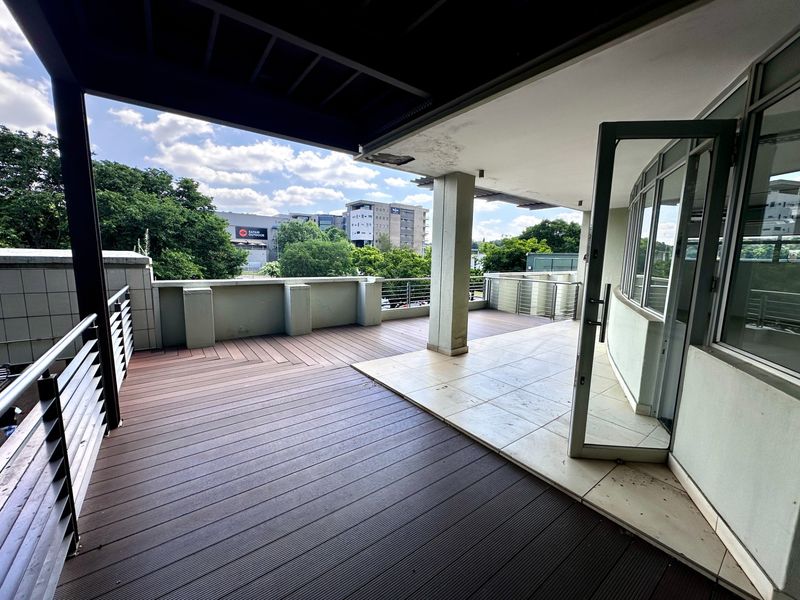 Spacious covered balcony featuring a mix of composite decking and tiled flooring, offering an open outdoor area with metal railings.