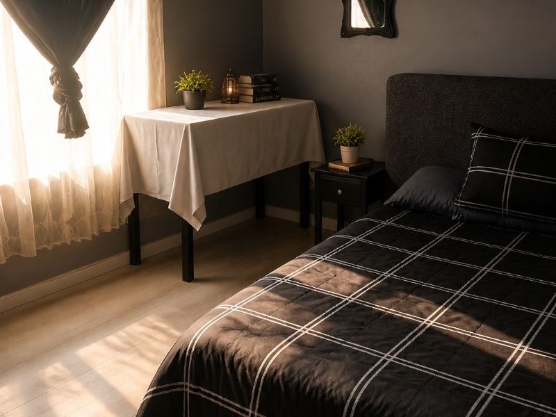 A well-lit bedroom featuring laminate flooring and dark-toned walls, creating a cozy and modern atmosphere with natural light streaming through the window.