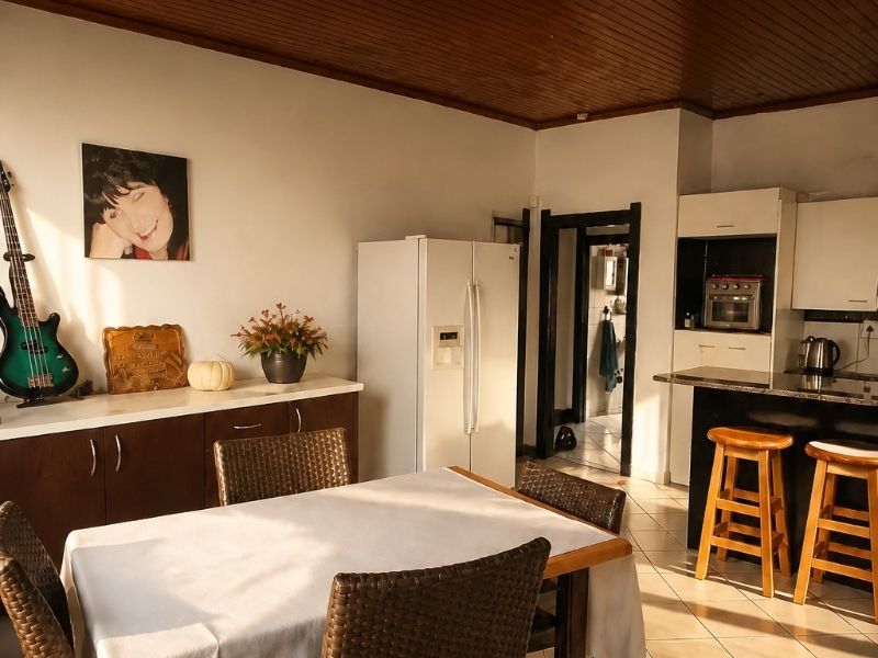 Open-plan kitchen and dining area featuring a timber ceiling, tiled floors, and a functional kitchen with granite countertops and a breakfast bar.