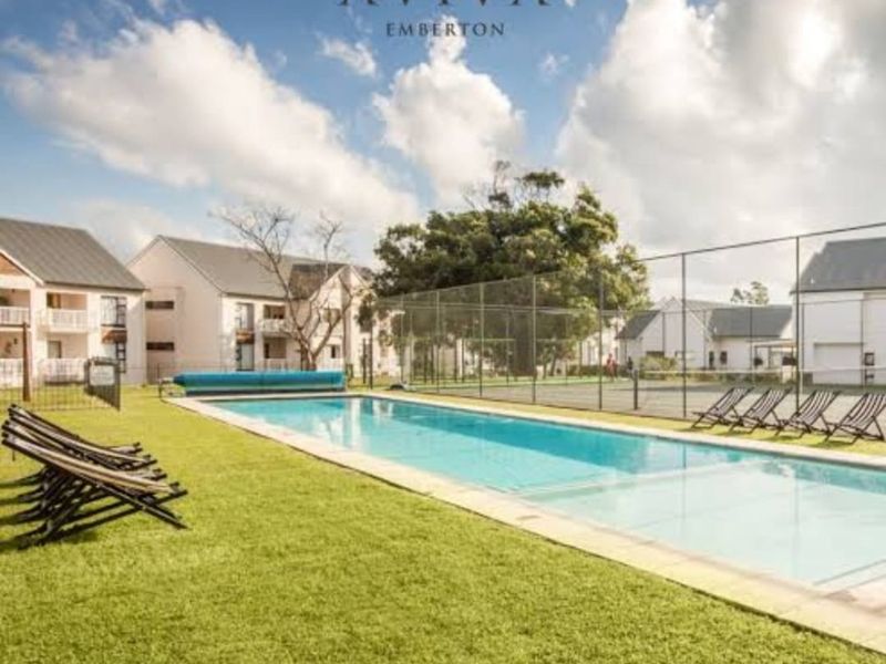 A well-maintained communal swimming pool and tennis court area set within a landscaped residential complex.