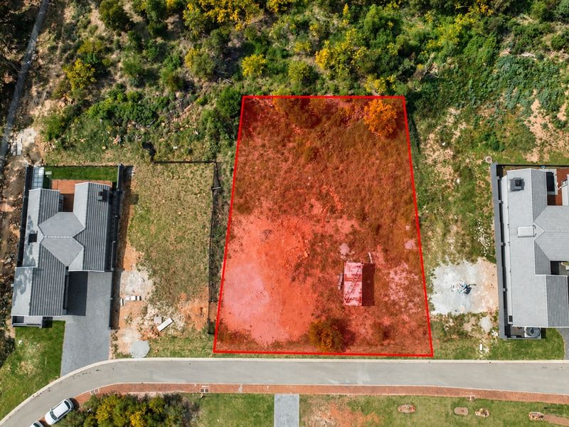 Aerial view of a vacant residential plot situated between two existing modern homes, highlighting the available building footprint.