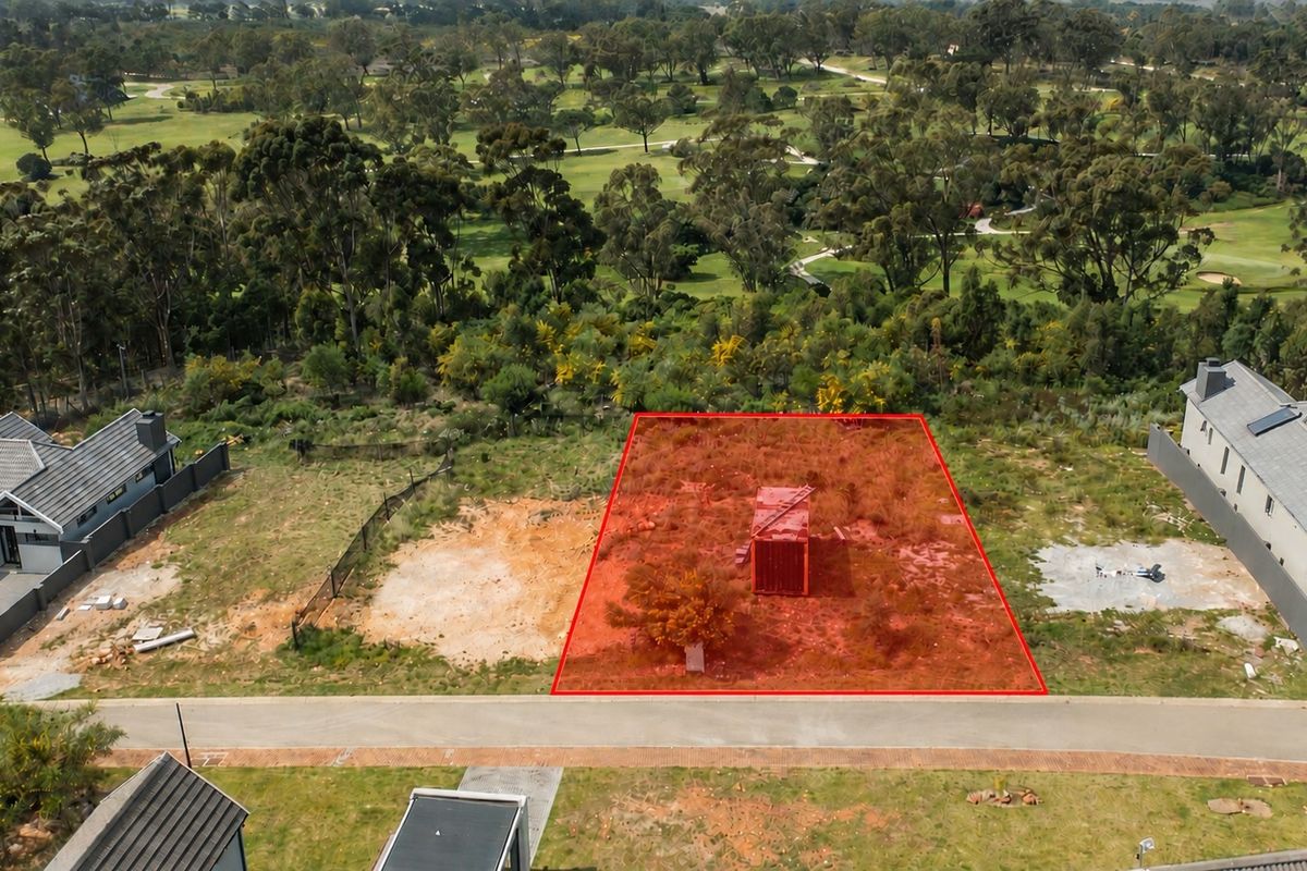 Aerial view of a vacant residential plot highlighted in red, situated in a developed estate with surrounding greenery.