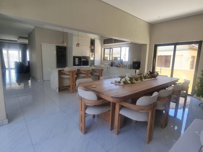 Spacious open-plan living and dining area featuring a modern kitchen with a central island, sleek cabinetry, and large sliding doors leading to the exterior.