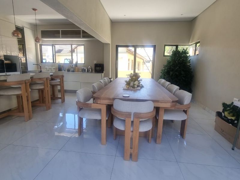 Spacious open-plan living area featuring a modern kitchen with a marble-look island, dining space, and large sliding doors leading to the exterior.