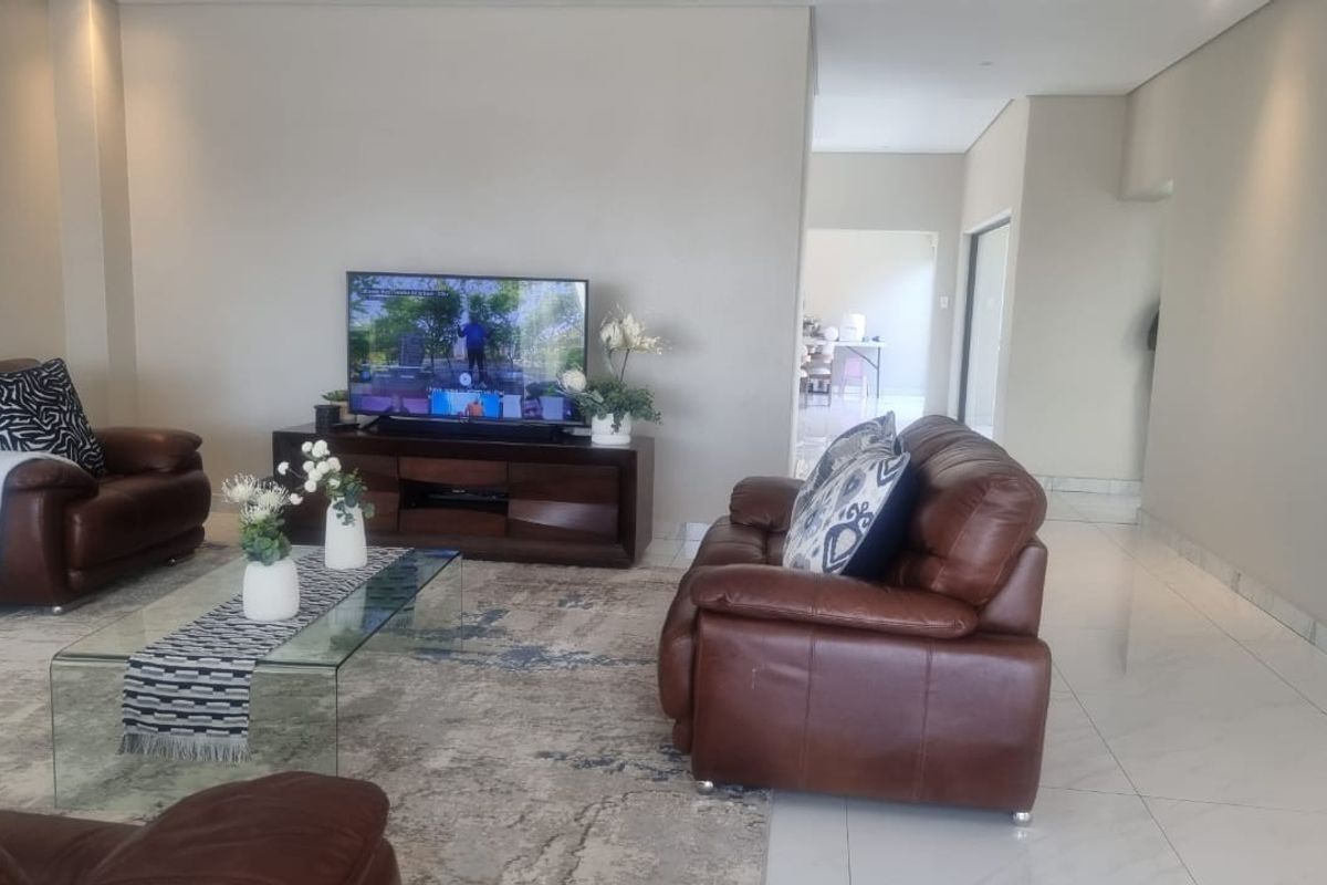 Spacious living room featuring polished tiled flooring, recessed downlighting, and an integrated air conditioning unit, offering a bright and open atmosphere.
