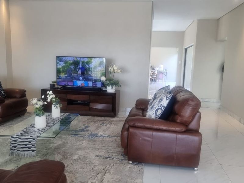 Spacious living room featuring polished tiled flooring, recessed downlighting, and an integrated air conditioning unit, offering a bright and open atmosphere.