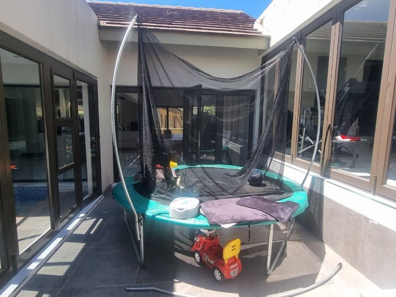 A covered patio area featuring tiled flooring and large aluminium-framed glass doors providing seamless access to the interior living spaces.