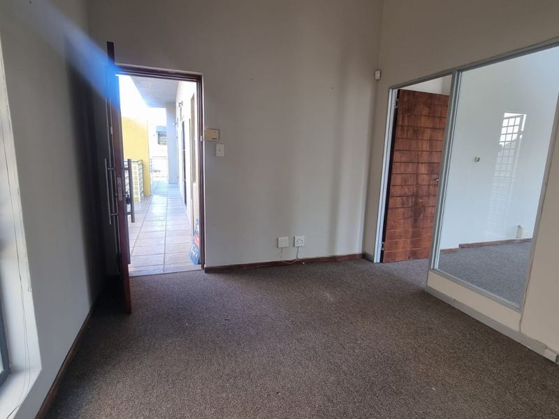An empty office space featuring carpet flooring, a glass partition, and direct access to an external walkway.