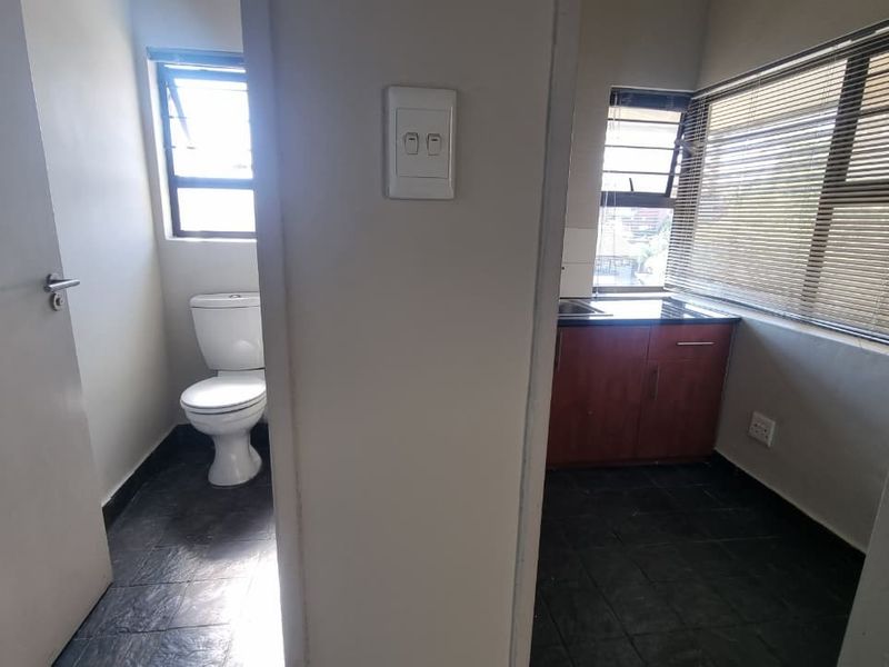 A functional utility space featuring a private toilet and a compact kitchenette area with built-in cabinetry and sink.